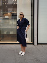 A blonde lady wears jumpsuit-like outfit